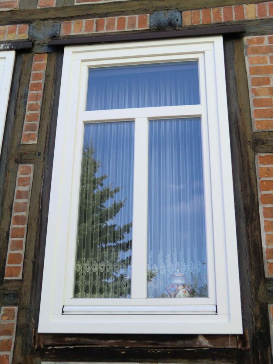 Weißes Fenster in Fachwerk- und Klinkerfassade